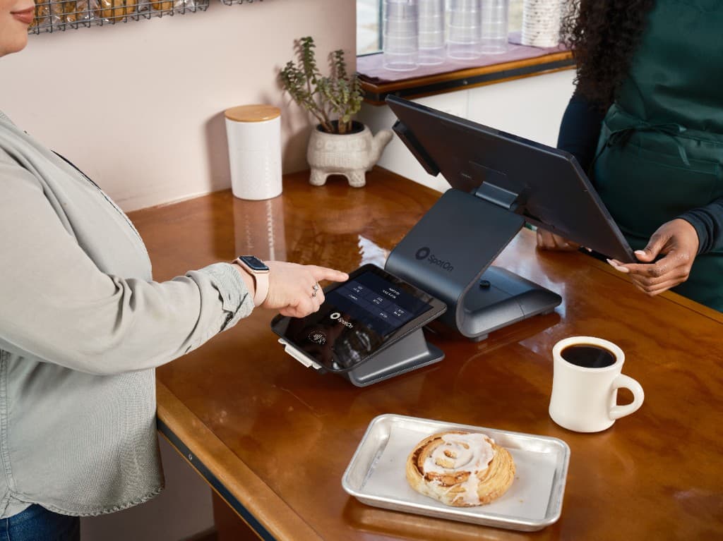 Klant betaalt aan de kassa in een bakkerij met koffie en gebak op de toonbank