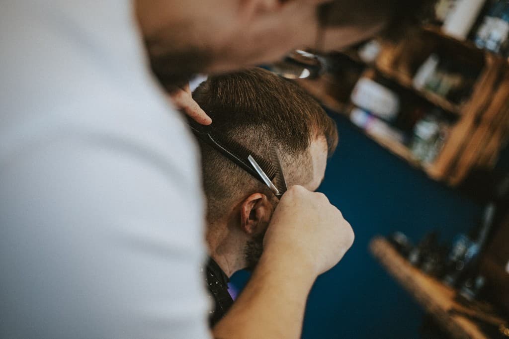 Kapper knipt haar met schaar en kam in de salon